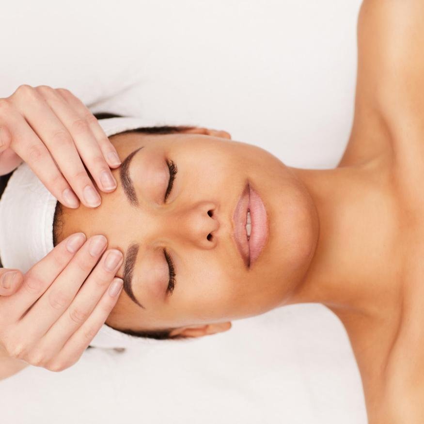 Above view portrait of beautiful mixed-race woman enjoying face massage in luxury spa, copy space